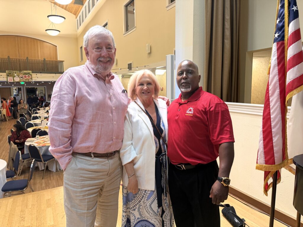 Three guests beside the flag
