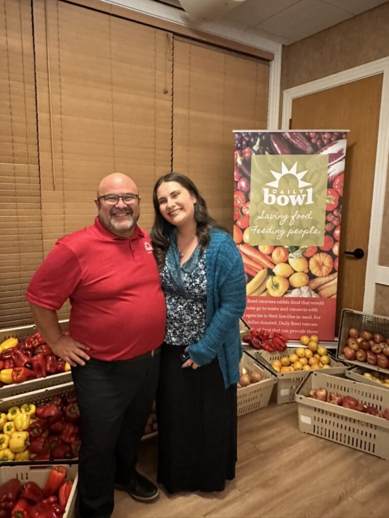 Two of the team beside crates of rescued peppers and apples